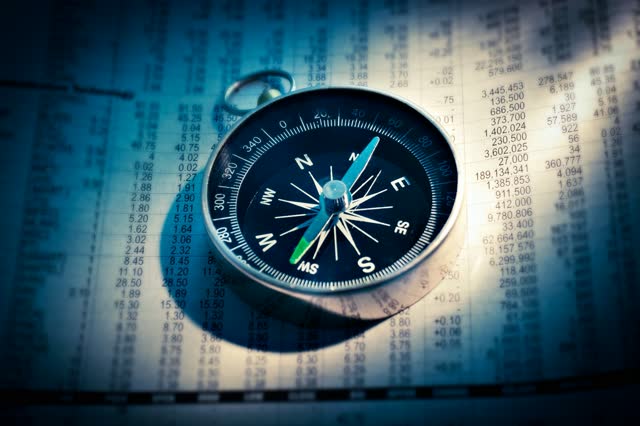 A compass resting on a page of financial figures