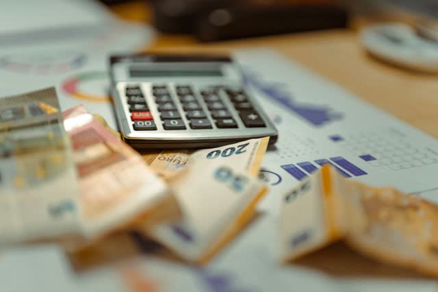Calculator and banknotes on top of a financial report